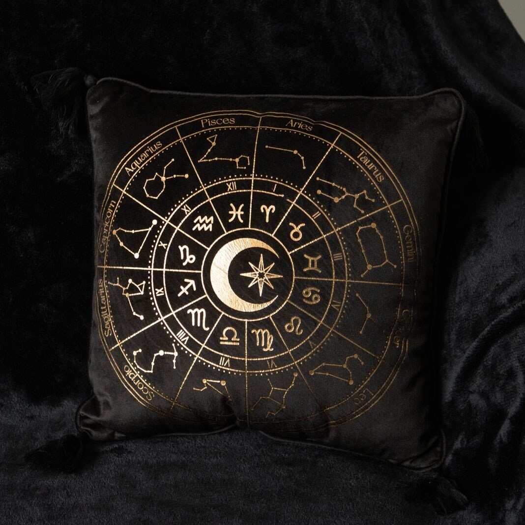 Black pillow with gold astrological design on a dark background