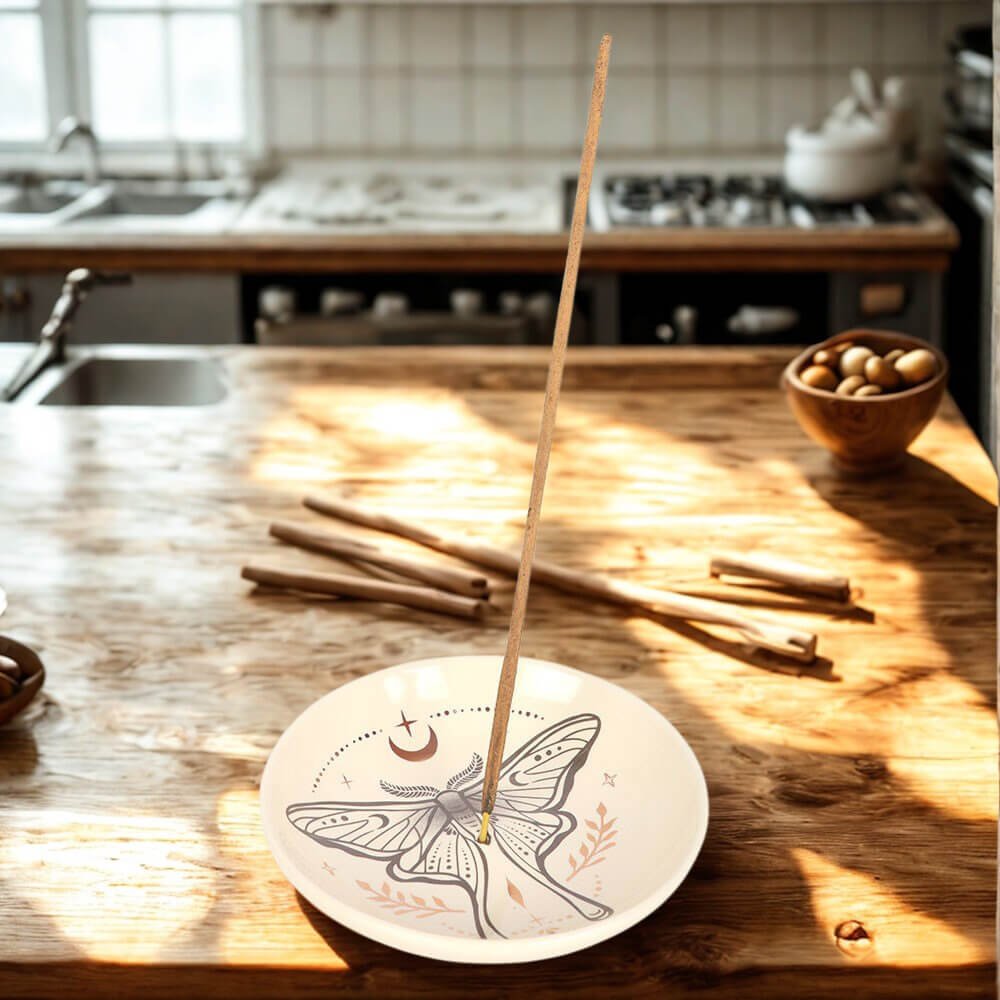 Incense stick on a decorative plate with a kitchen in the background