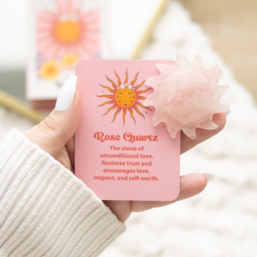 Hand holding a pink card with a sun illustration and text about Rose Quartz