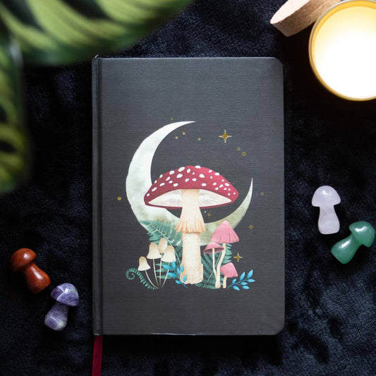 Black notebook with mushroom design on a dark surface with decorative items.