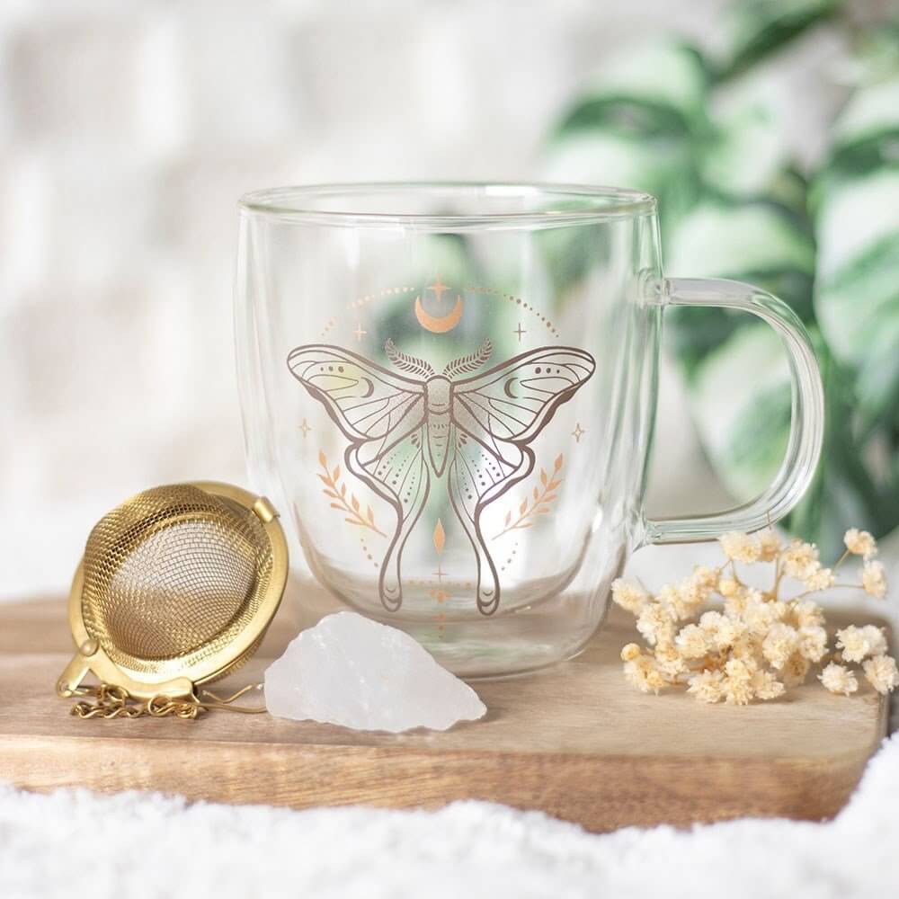 Clear glass mug with butterfly design on a wooden surface with decorative elements.