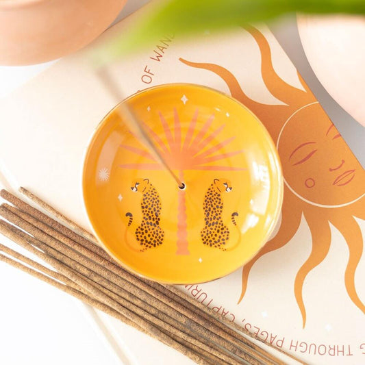 Decorative dish with animal design on a surface with incense sticks and a magazine.
