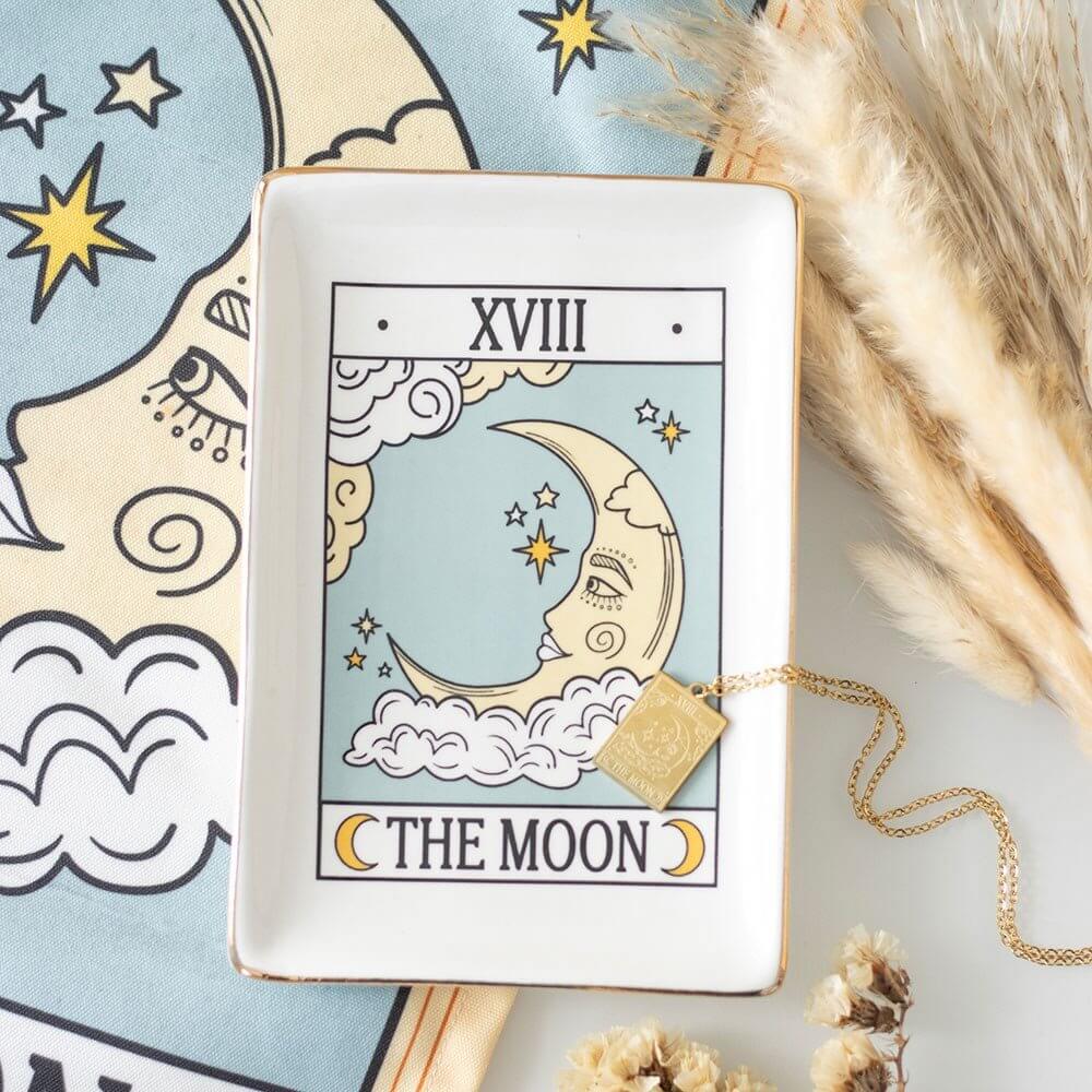Tarot card with 'The Moon' symbol and a necklace on a decorative background