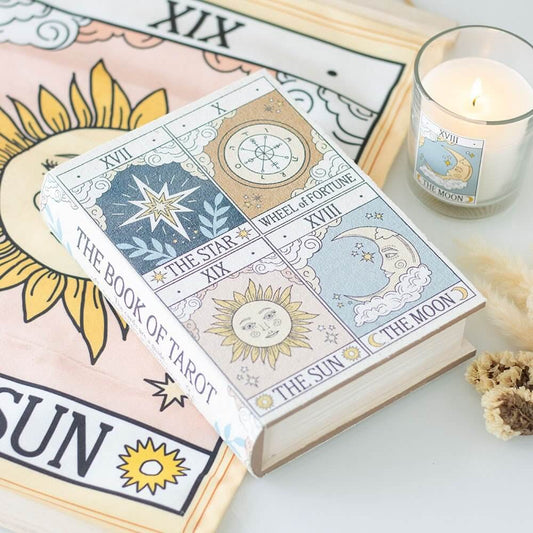 Book of Tarot with tarot cards and a candle on a white surface